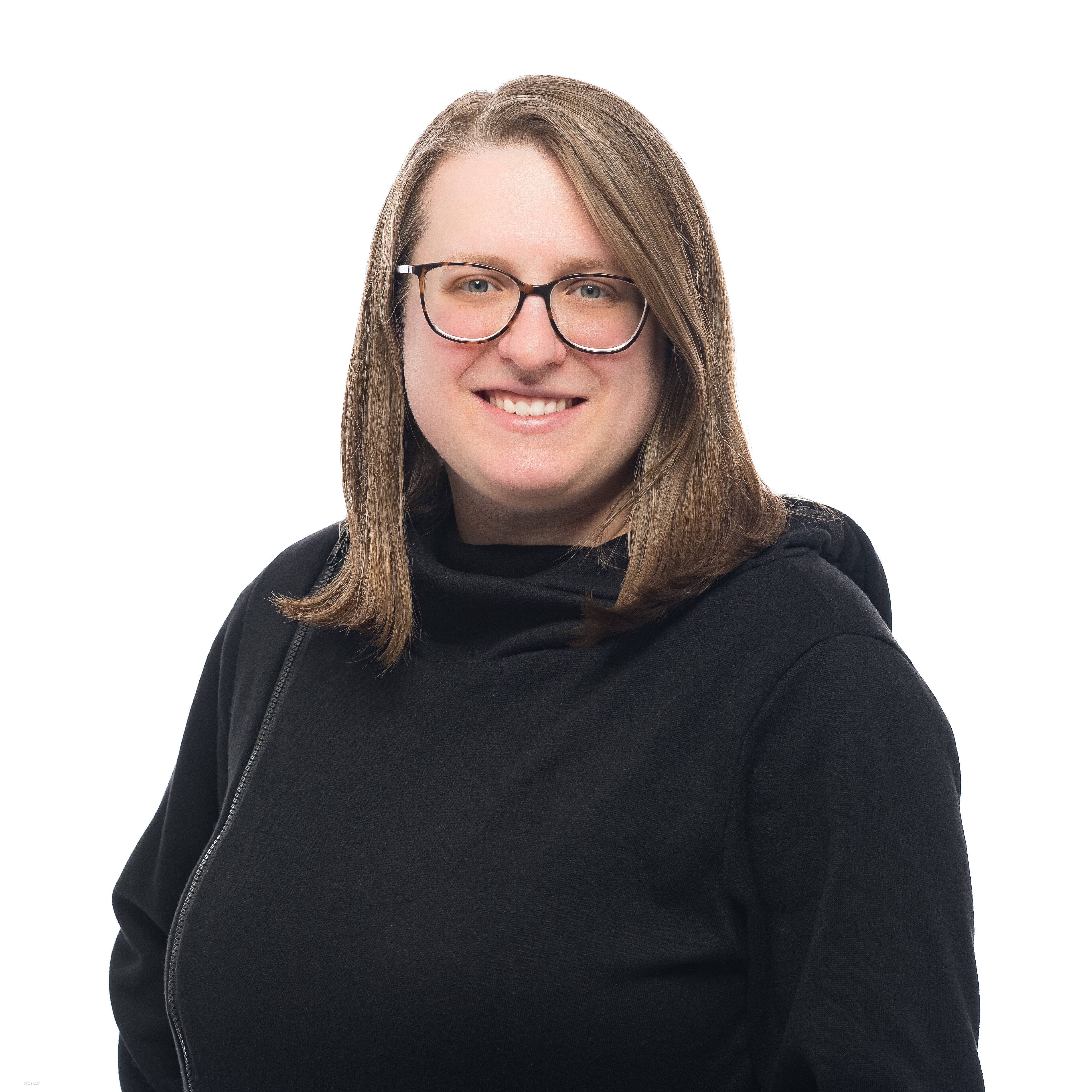 headshot of Jamie Aukofer on a white background. Jamie is wearing a black hoodie and dark-rimmed glasses